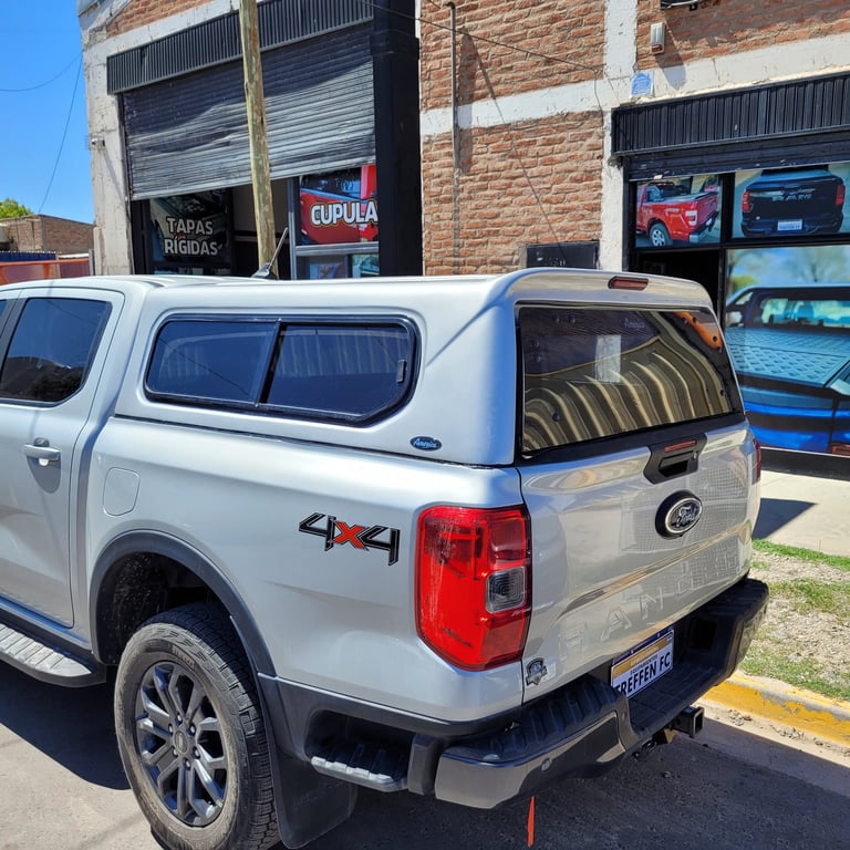 White pickup truck with camper shell parked outside brick warehouse building with storefronts