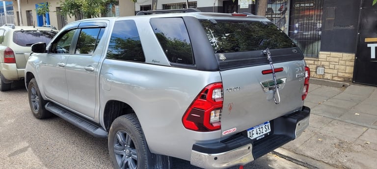 Silver Toyota pickup truck parked on street with red taillights visible from rear three-quarter view