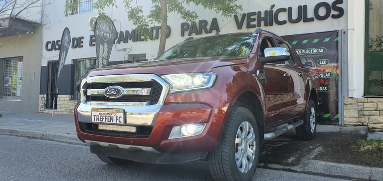 Red Ford Ranger pickup truck parked in front of an auto repair shop with Spanish signage
