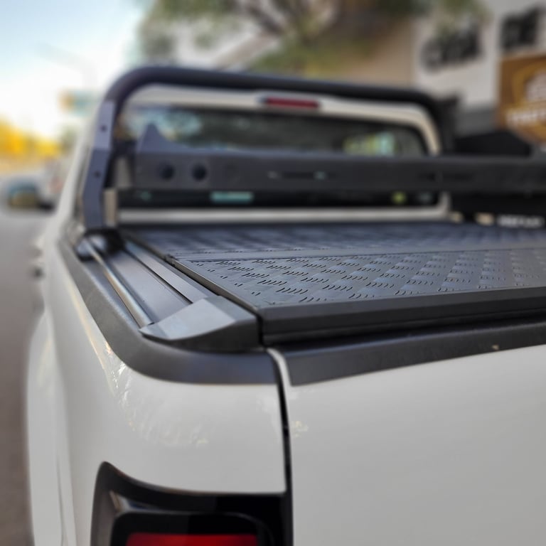 Close-up of a white pickup truck bed with a black tonneau cover, parked in daylight