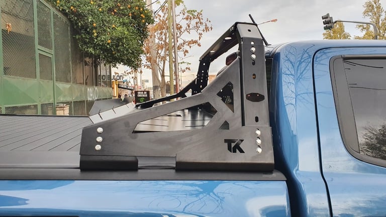 Blue pickup truck bed with black TK rollbar and sport tonneau cover in urban parking lot