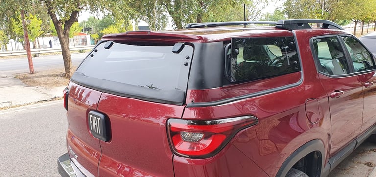 Red pickup truck with cargo cover parked on a tree-lined residential street