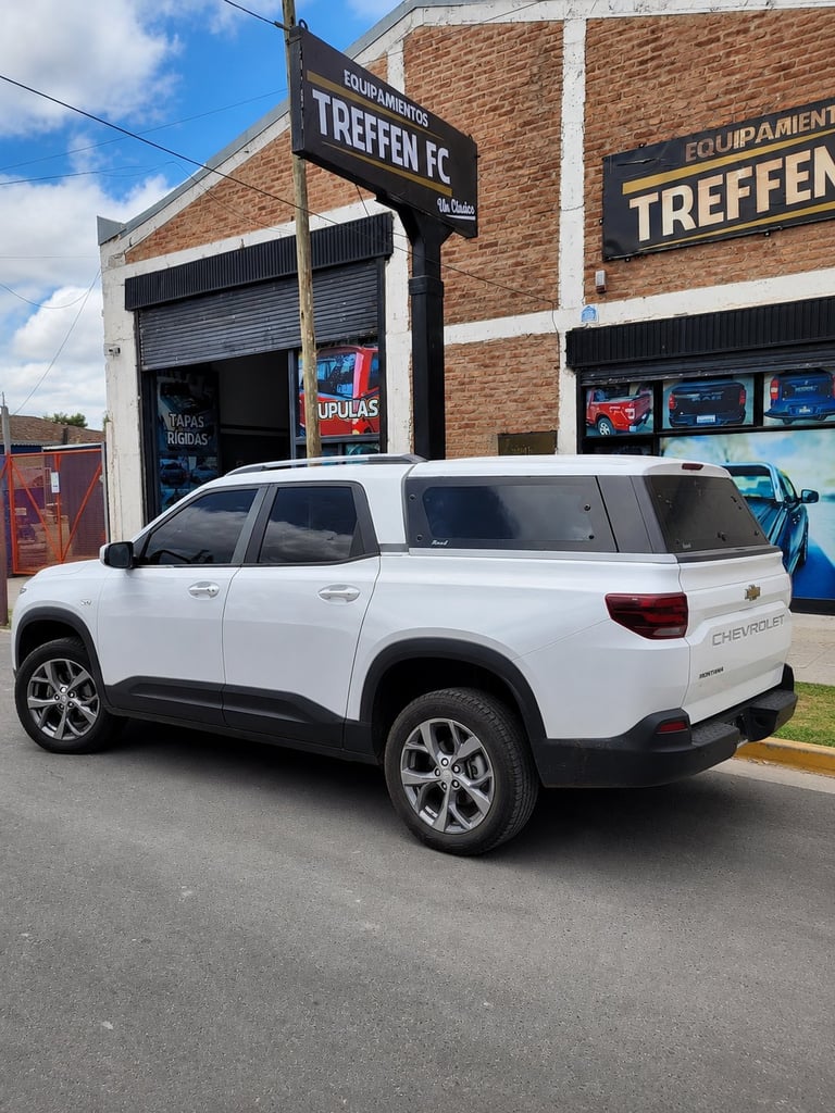 White Chevrolet SUV parked in front of Treffen FC auto shop with brick building and signage