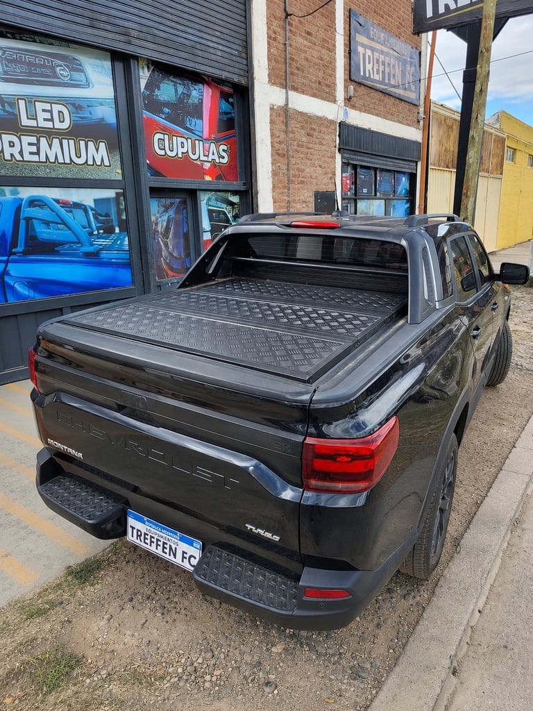 Black pickup truck with tonneau cover parked outside auto shop storefront