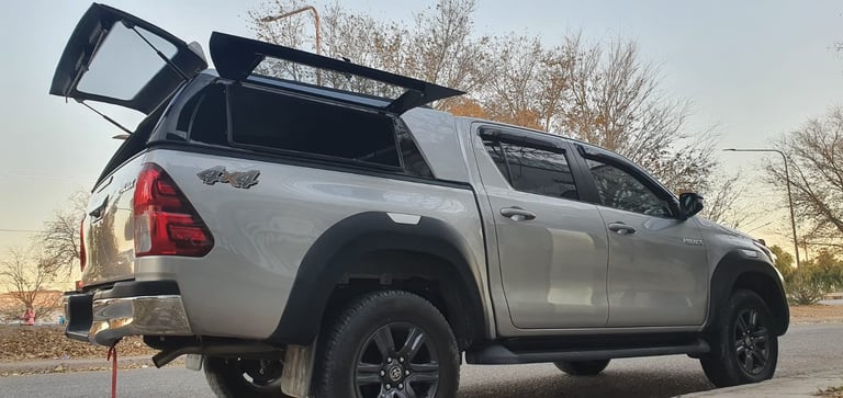 White pickup truck with open tonneau cover and roof rack parked outdoors at dusk