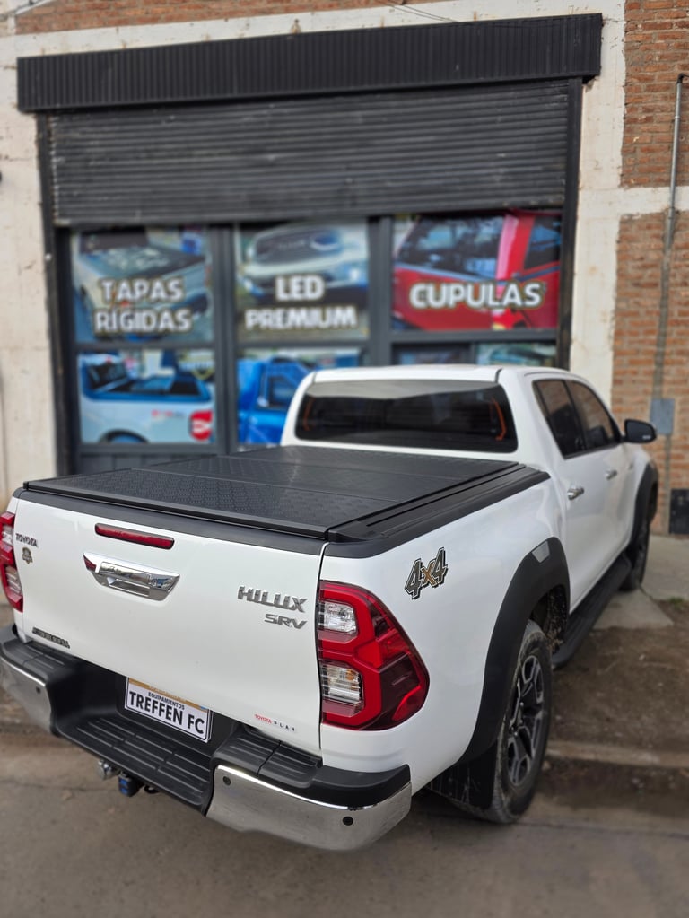 White pickup truck with tonneau cover parked in front of auto parts store with signage