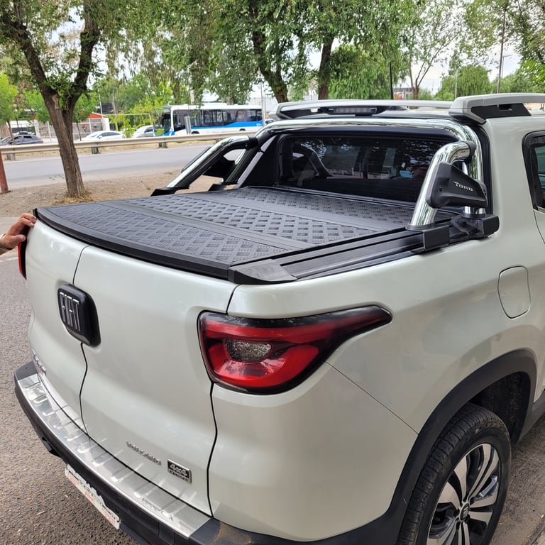 White pickup truck with open tonneau cover bed, parked on street with trees in background
