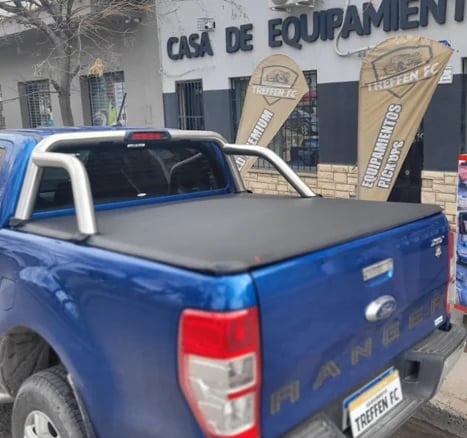 Blue pickup truck with black tonneau cover in an auto parts store parking lot