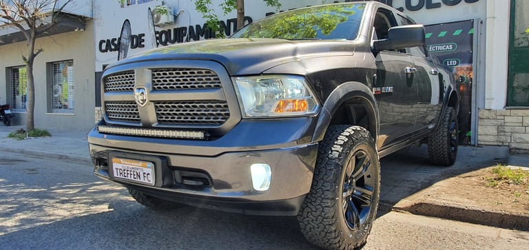 Black Ram pickup truck with chrome grille parked on a street in front of a building