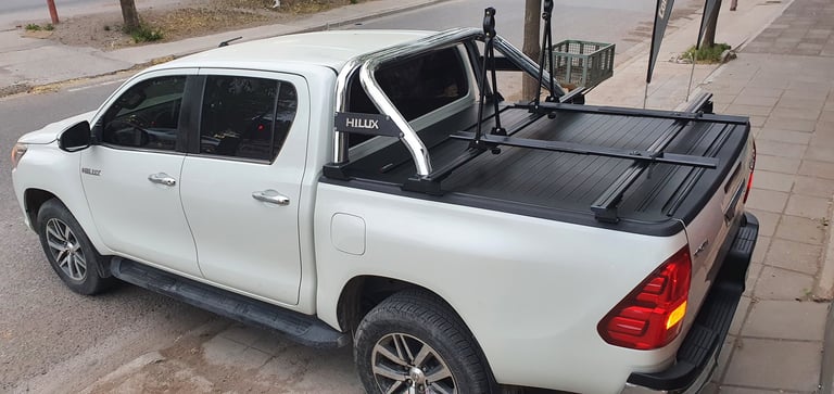 White pickup truck with open driver door and roof rack mounted on paved surface