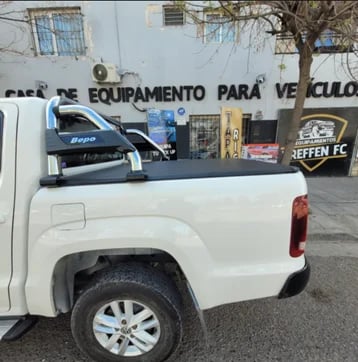 White pickup truck loaded with equipment in urban setting, storefront visible in background