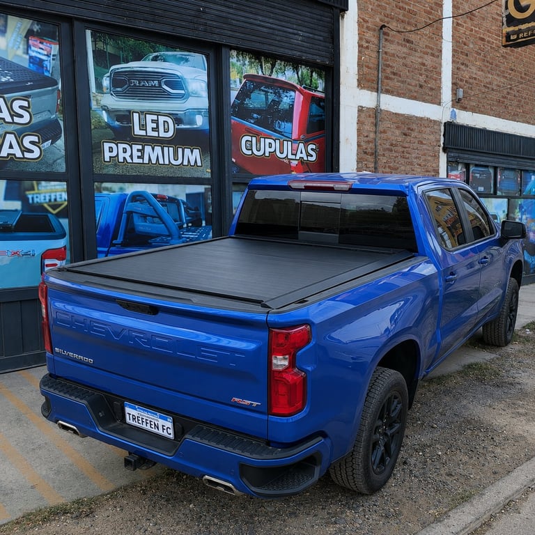 Blue pickup truck with tonneau cover parked outside auto accessories shop with signage