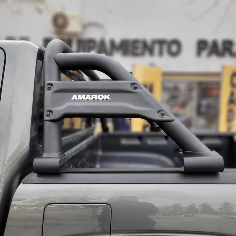 Black roll bar with AMAROK branding mounted on truck bed, building in background